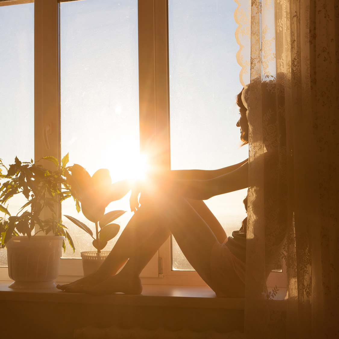 A woman sitting on a sunny windowsil